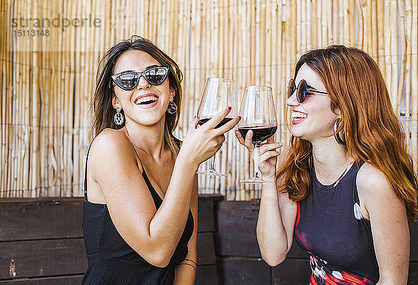 Zwei glückliche Frauen bei einem Glas Rotwein in einer Bar