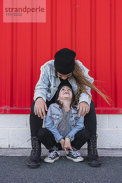 Glückliche Teenagerin und kleine Schwester sehen sich an