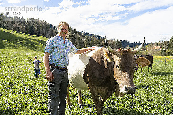 Porträt eines selbstbewussten Landwirts mit Kuh auf der Weide