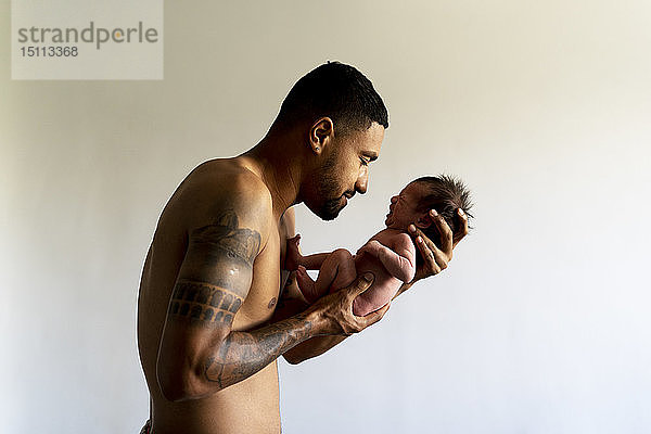 Zärtlicher Vater hält sein weinendes nacktes Neugeborenes