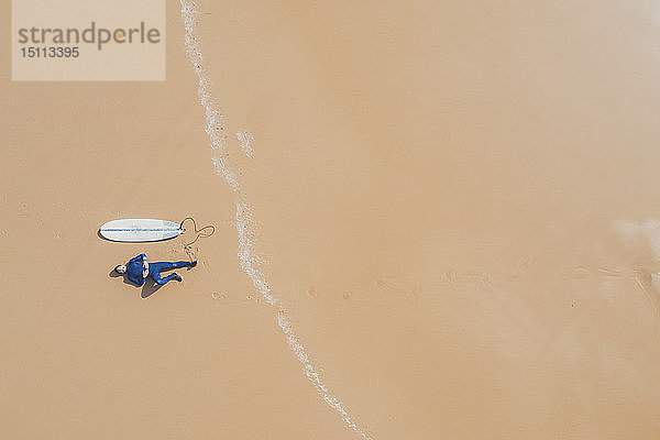 Portugal  Algarve  Sagres  Praia da Mareta  Luftaufnahme eines Mannes  der neben einem Surfbrett am Strand liegt