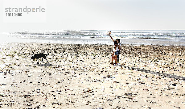 Drei Frauen mit Hund beim Spaziergang am Strand