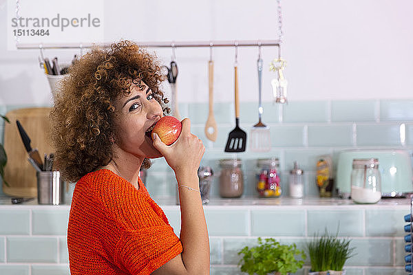 Porträt einer Frau  die in einer Büroküche einen Apfel isst