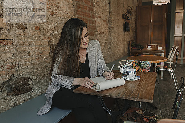 Junge Frau macht Notizen in einem Cafe