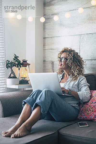 Frau benutzt Laptop auf der Couch zu Hause