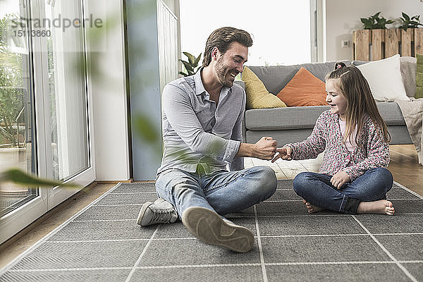 Junger Mann und kleines Mädchen sitzen zu Hause und spielen Papier  Schere  Stein
