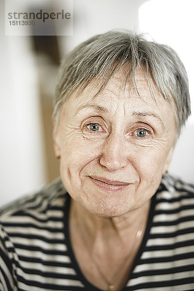 Porträt einer glücklichen älteren Frau mit kurzen Haaren  die mit Tränen in den Augen lächelt