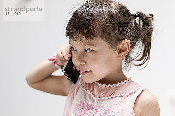 Porträt eines lächelnden kleinen Mädchens am Telefon