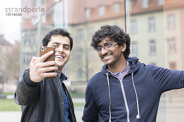 Porträt von lächelnden Freunden  die sich mit dem Smartphone selbstständig machen