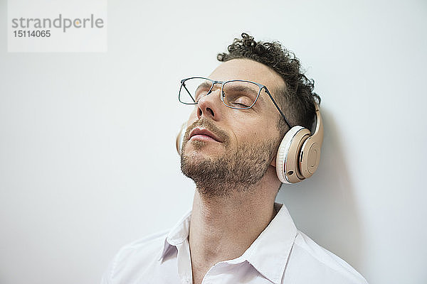 Geschäftsmann mit geschlossenen Augen  der mit Kopfhörern Musik hört