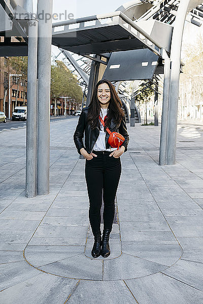 Glückliche junge Frau mit roter Hüfttasche in der Stadt