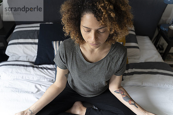 Frau  die Yoga praktiziert  auf dem Bett sitzt  meditiert