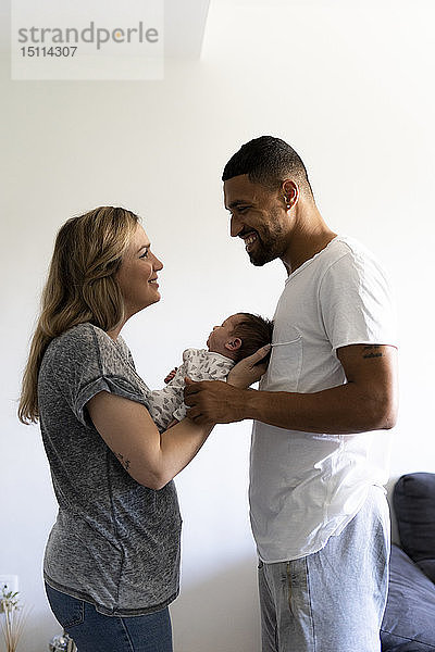 Glückliche Eltern halten ihr Neugeborenes zu Hause