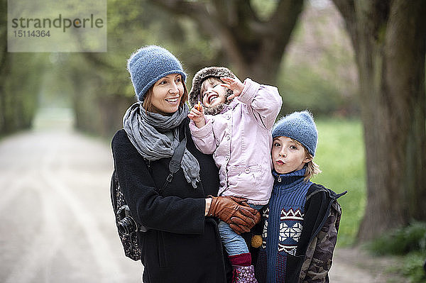 Porträt einer glücklichen Mutter mit Sohn und kleiner Tochter in einem Park