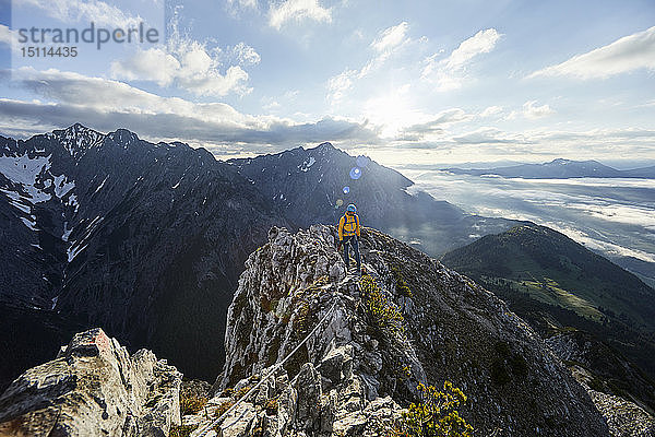 Österreich  Tirol  Gnadenwald  Hundskopf  männlicher Bergsteiger im Fels stehend im Morgenlicht