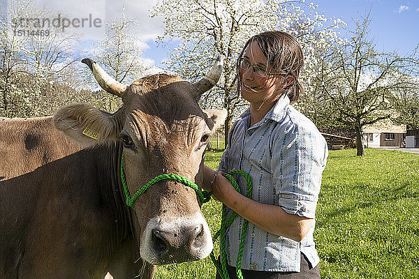 Lächelnder Landwirt mit einer Kuh auf der Weide