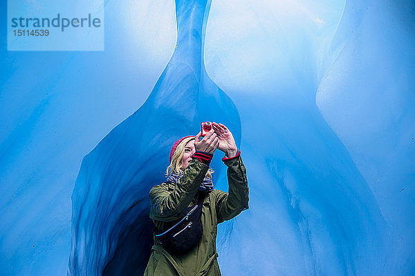 Frau macht ein Foto in einer Eishöhle  Fox Glacier  Südinsel  Neuseeland