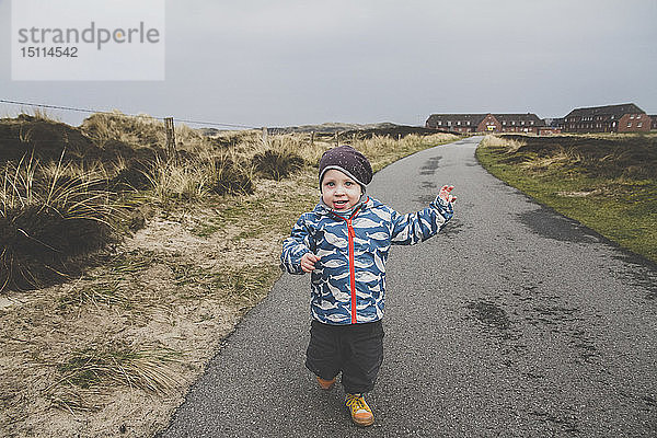 Porträt eines kleinen Jungen  der auf einer leeren Straße rennt  Sylt  Deutschland