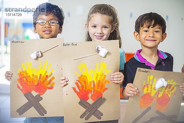 Porträt von lächelnden Kindern  die Bilder von Feuer im Kindergarten präsentieren