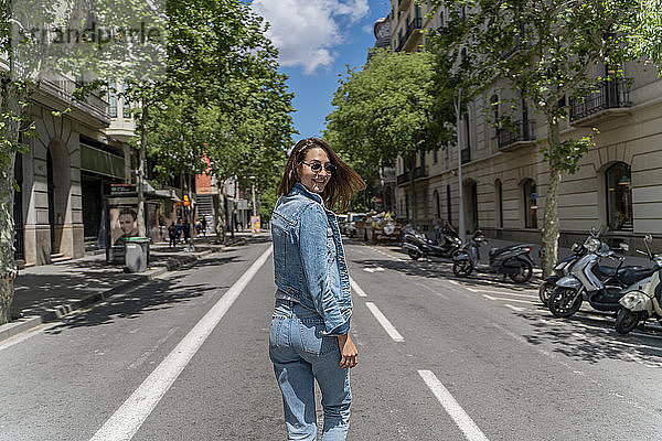 Junge Frau geht auf einer Straße und blickt zurück in Barcelona