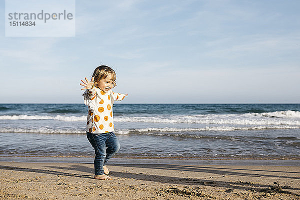 Glückliches kleines Mädchen läuft barfuss am Strand