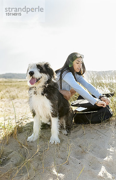 Junge Frau mit Hund und Gitarre am Strand