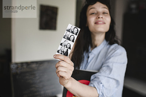 Frau hält Fotos von sich mit ihrem Freund in der Hand