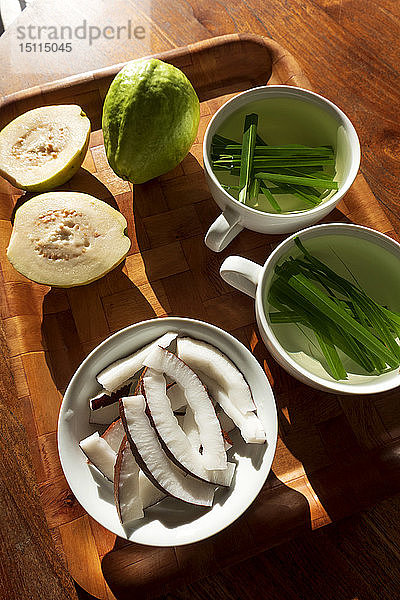 Seychellen  Holztablett mit Guave  Schale mit frischen Kokosnussscheiben und Tassen mit Zitronengras-Tee