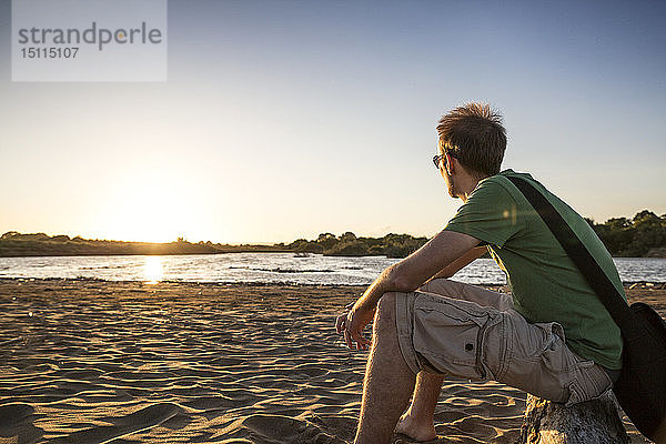 Italien  Sizilien  junger Mann genießt den Sonnenuntergang am Strand von Eloro