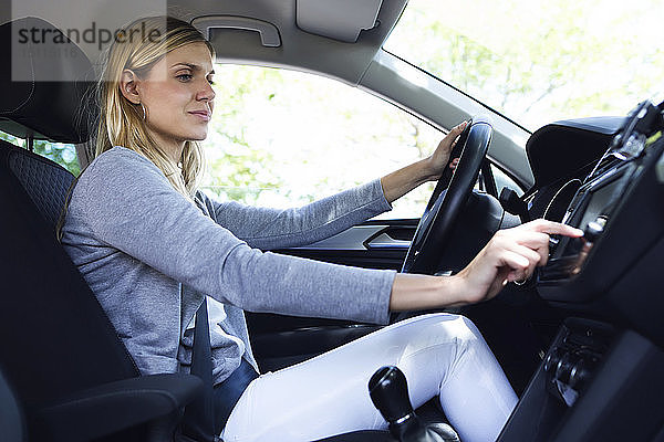 Junge Fahrerin wählt in ihrem Auto einen Radiosender