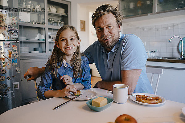 Porträt von Vater und Tochter zu Hause am Frühstückstisch sitzend