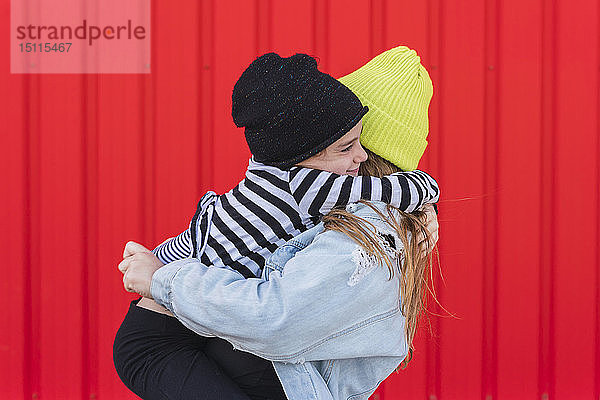 Glückliches kleines Mädchen umarmt ältere Schwester