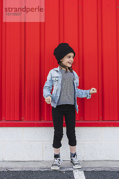 Modisches kleines Mädchen mit Mütze  Jeansjacke und Turnschuhen