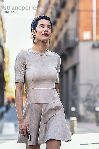 Modische junge Frau in einem Kleid geht in der Stadt spazieren