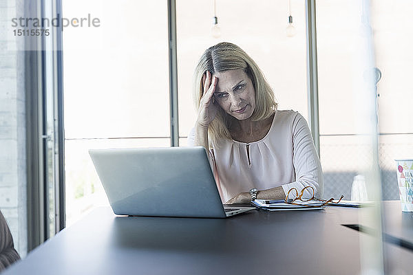 Gestresste Geschäftsfrau benutzt Laptop im Büro