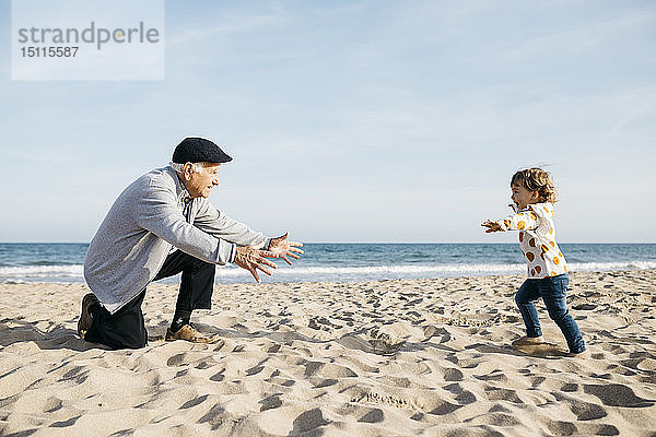 Großvater spielt mit seiner Enkelin am Strand