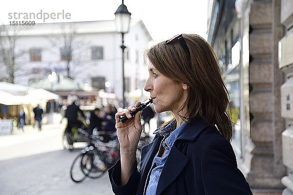 Reife Frau raucht elektronische Zigarette in der Stadt