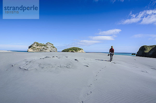 Frau wandert in den weißen Sanddünen am Wharariki Beach  Südinsel  Neuseeland