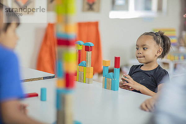 Mädchen betrachtet Turm aus Bauklötzen im Kindergarten