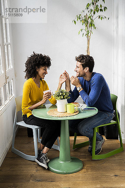 Glückliches  liebevolles Paar sitzt zu Hause am Tisch