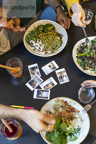 Gruppe von Freunden beim Mittagessen in einem Restaurant mit Sofortfotos auf dem Tisch