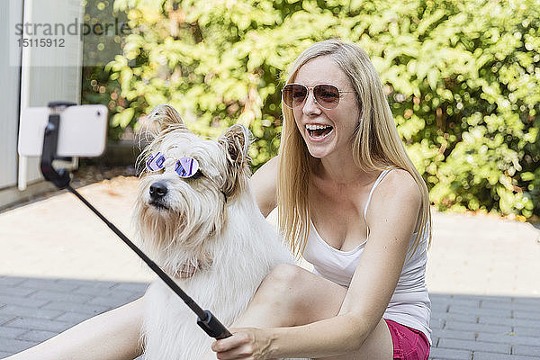 Glückliche Frau  die mit ihrem Hund  der eine Sonnenbrille trägt