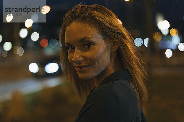 Porträt einer jungen Frau in der Stadt bei Nacht