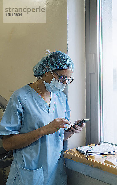 Ärztin  die im Krankenhaus ein Smartphone benutzt und sich auf eine Operation vorbereitet