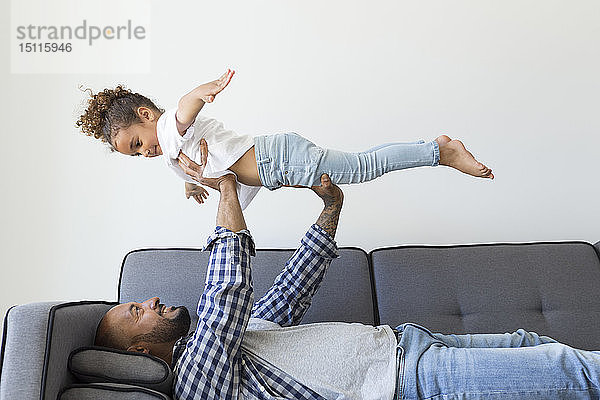 Glückliche Vater und Tochter spielen zu Hause auf der Couch