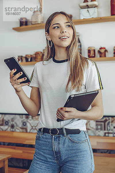 Porträt einer jungen Frau  die in einem Cafe eine Tablette hält