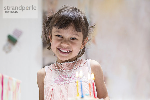 Porträt eines glücklichen kleinen Mädchens mit brennenden Kerzen auf Geburtstagskuchen