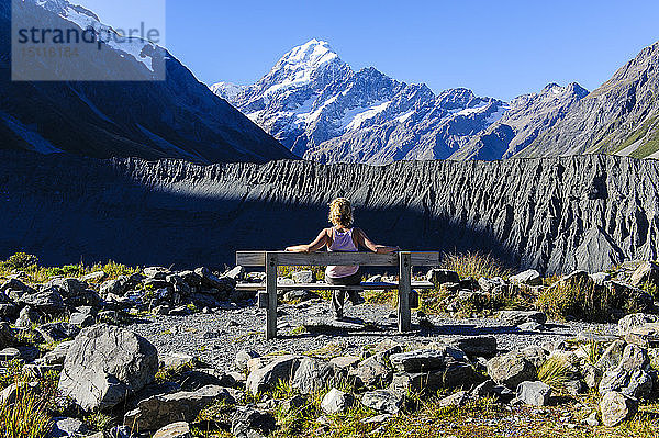 Frau sitzt auf einer Bank und genießt den Blick auf Mount Cook  Südinsel  Neuseeland