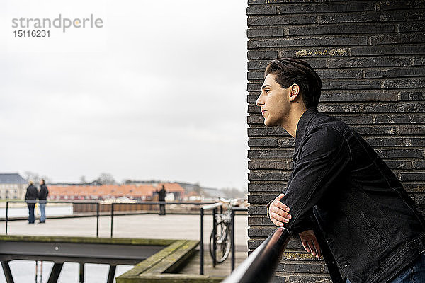 Dänemark  Kopenhagen  junger Mann lehnt am Wasser an einem Geländer