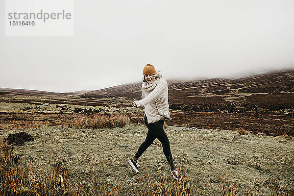 UK  Schottland  Isle of Skye  glückliche junge Frau läuft in ländlicher Landschaft